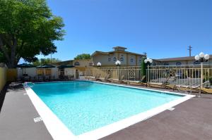 a swimming pool with chairs and a fence at Best Western Bishop Lodge in Bishop
