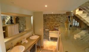 a bathroom with two sinks and a stone wall at Les Demeures de Marie in Pacé