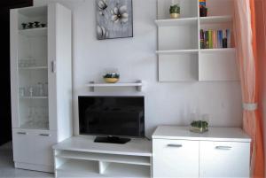 - un salon avec une télévision et des étagères blanches dans l'établissement Corona 204 Apartments Casasol, à Nerja