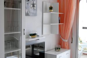 Cette chambre dispose d'étagères blanches et d'un rideau orange. dans l'établissement Corona 204 Apartments Casasol, à Nerja