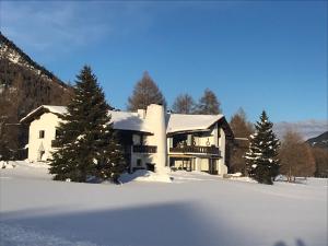 a large house in the snow with snow covered trees at Chesa Suot Ovas in Sils Maria