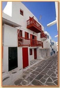 Edificio blanco con puertas rojas y balcón en Studio Eleni, en Mykonos ciudad