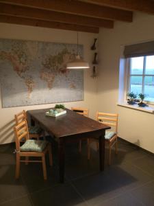 a dining room table with chairs and a map on the wall at Boerengastenverblijf De Kromme Rijn in Cothen
