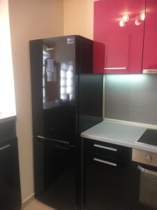 a black refrigerator in a kitchen with red cabinets at Stylish spacious flat in Sofia