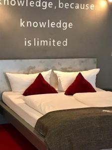 a bed with two red pillows on it with the words knowledge knowledge is limited at home2be apartments in Wuppertal