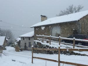 a house covered in snow with a car parked next to it at La Grange du Lac de Cantalès in Lacapelle-Viescamp