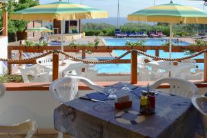 un restaurant avec une table et des chaises ainsi qu'une piscine dans l'établissement Villaggio La Siesta, à Marina di Camerota