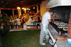 a man standing next to a grill in a restaurant at Villaggio La Siesta in Marina di Camerota