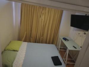 a room with a bed and a table and a television at Departamento Teniente Uribe in Antofagasta