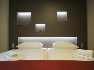 2 bedden met witte lakens en kussens in een kamer bij Hotel Neuthor in Ulm