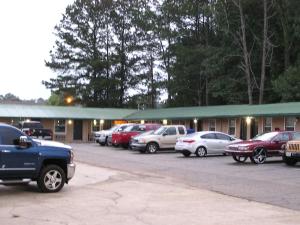 eine Gruppe von Autos, die auf einem Parkplatz geparkt sind in der Unterkunft American Inn Motel in Many