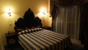 1 dormitorio con 1 cama con manta a rayas y ventana en Albergaria Malaposta, en Pegões
