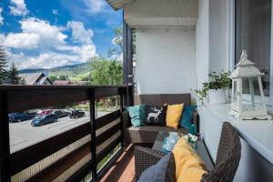 a balcony with a couch and a view of a street at Apartamentylove - Apartament Zborowski Centrum, 100m do Krupówek in Zakopane