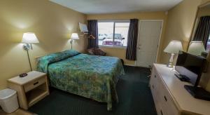 a hotel room with a bed and a television at Westwood Motel 100 Mile House in One Hundred Mile House