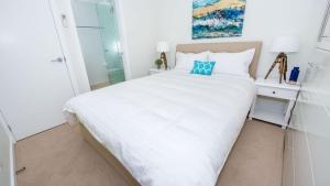 1 dormitorio con cama blanca y almohada azul en SUNSET@CORLETTE, en Corlette