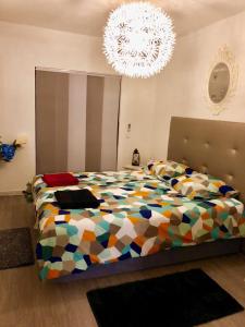 a bedroom with a colorful bed and a chandelier at ColinaSol Vale Centeanes Appartement vue mer in Carvoeiro +26 photos