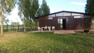 czerwona szopa ze stołem i krzesłami na polu w obiekcie Az.Agr.Cascina Moretta w mieście Momo +37 zdjęć