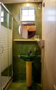 Baño verde con lavabo y espejo en Grimani Pension, en Nauplia