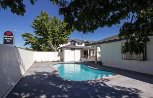 a swimming pool in front of a house at ASURE Phoenix Motor Inn in Blenheim