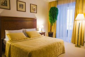 Royal Plaza في نفتيوغانسك: غرفة نوم بسرير مع شراشف صفراء ونافذة