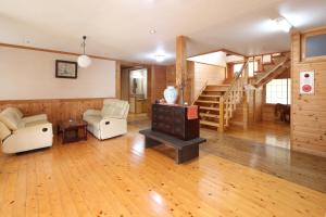 a living room with wooden floors and a staircase at Minshuku Asogen in Aso