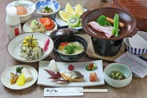 a table topped with plates and bowls of food at Minshuku Asogen in Aso