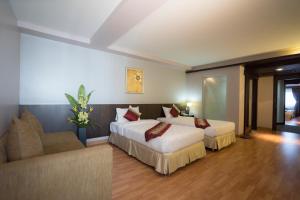 a hotel room with two beds and a couch at Kiss Gardenhome Chic Hotel in Hat Yai