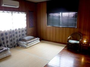 a room with a window and a pile of mattresses at Okinawa Hostel Yanbaru Fukuro in Nago