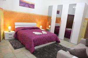 Un dormitorio con una cama púrpura con dos animales de peluche. en Agriturismo Il Pavone, en Torre Lapillo