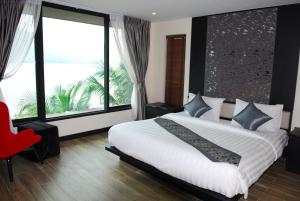 a bedroom with a large bed and a large window at Monsane River Kwai Resort & Spa in Kanchanaburi