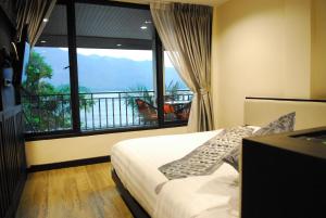 a bedroom with a bed and a large window at Monsane River Kwai Resort & Spa in Kanchanaburi City