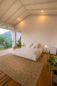 a large white bed in a room with a large window at Tea Heights in Kandy