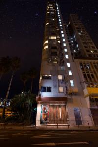 a tall building with lights on it at night at The Aberdeen Harbour by Ovolo in Hong Kong