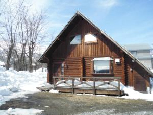 a log cabin in the snow with a window at Log Cottage Villa Happo in Hakuba