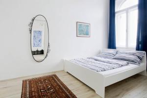 ブダペストにあるApartment Andrassyの白いベッドルーム(ベッド1台、鏡付)