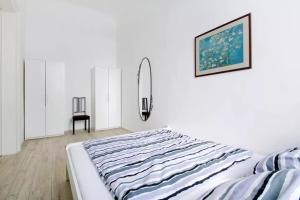 een witte slaapkamer met een bed en een foto aan de muur bij Apartment Andrassy in Boedapest