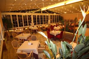 a restaurant with white tables and chairs and plants at Hotel Boutique Restaurant Gloria in Tirana