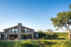 una casa en un campo con un árbol en Mjejane Bush Camp by Dream Resorts, en Hectorspruit