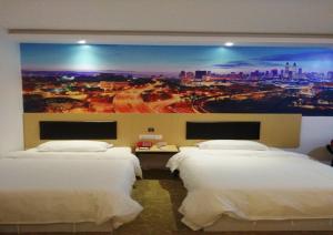 2 camas en una habitación de hotel con un cuadro en la pared en JUNYI Hotel Jiangxi Ganzhou South Gate Square Wenqing Road, en Ganzhou