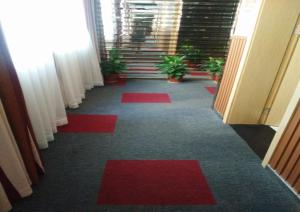 - un couloir avec moquette rouge et tapis rouges dans l'établissement JUNYI Hotel Jiangxi Ganzhou South Gate Square Wenqing Road, à Ganzhou