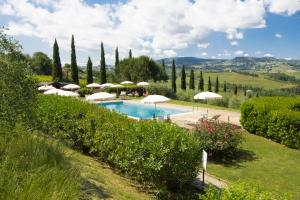 a pool in a garden with umbrellas and trees at Il Rosolaccio in San Gimignano +25 photos