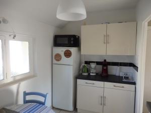 Una cocina con gabinetes blancos y un refrigerador blanco. en Appartement Liartais - Accueil Chevaux - Horse Friendly, en Liart