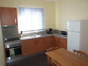 eine Küche mit einem Tisch und einem weißen Kühlschrank in der Unterkunft Paraiso das Flores in Estreito da Calheta