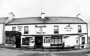 een zwart-witte foto van een gebouw met banken vooraan bij Vaughans Anchor Inn in Liscannor