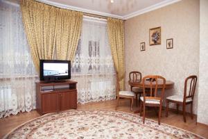 a living room with a television and a table and chairs at Tarkho Hotel in Makhachkala