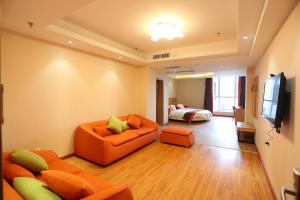 sala de estar con sofá naranja y TV en JUNYI Hotel Hebei Shijiazhuang Pingshan Town Wanshou Road, en Pingshan