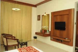 a hotel room with a bed and a tv at Ponnis Grand Inn in Chennai