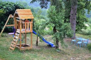 un parque infantil de madera con un tobogán y una escalera en Les Terrasses De Bessou, en Clermont-Dessous