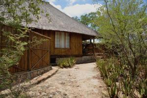 a wooden house with a thatched roof and a pathway at Moholoholo Mountain View in Hoedspruit
