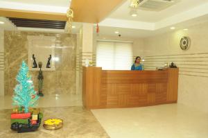 a woman standing at a counter in a lobby with a christmas tree at Ponnis Grand Inn in Chennai